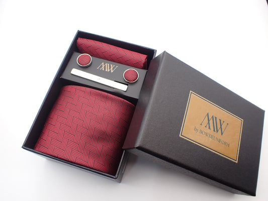 A black gift box containing a dark burgundy red men's tie with a geometric basketweave woven texture, matching pocket square, cufflinks, and a tie clip.