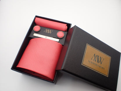 A black gift box featuring a bright watermelon pink textured men's necktie, a matching pocket square, round cufflinks, and a silver tie bar.