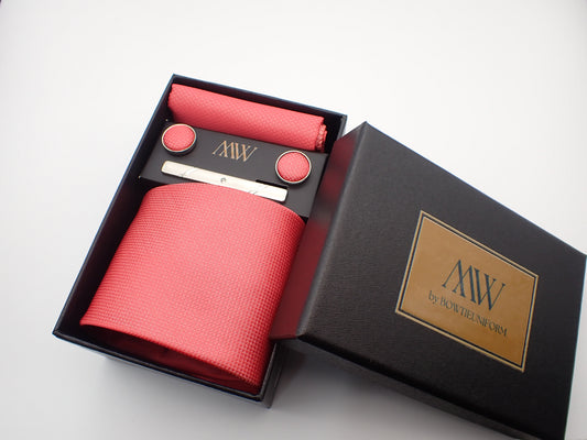 A black gift box featuring a bright watermelon pink textured men's necktie, a matching pocket square, round cufflinks, and a silver tie bar.